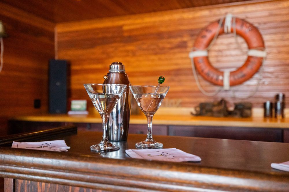 Wooden restaurant interior with rustic paneled walls and warm lighting illuminates empty dining tables and chairs.