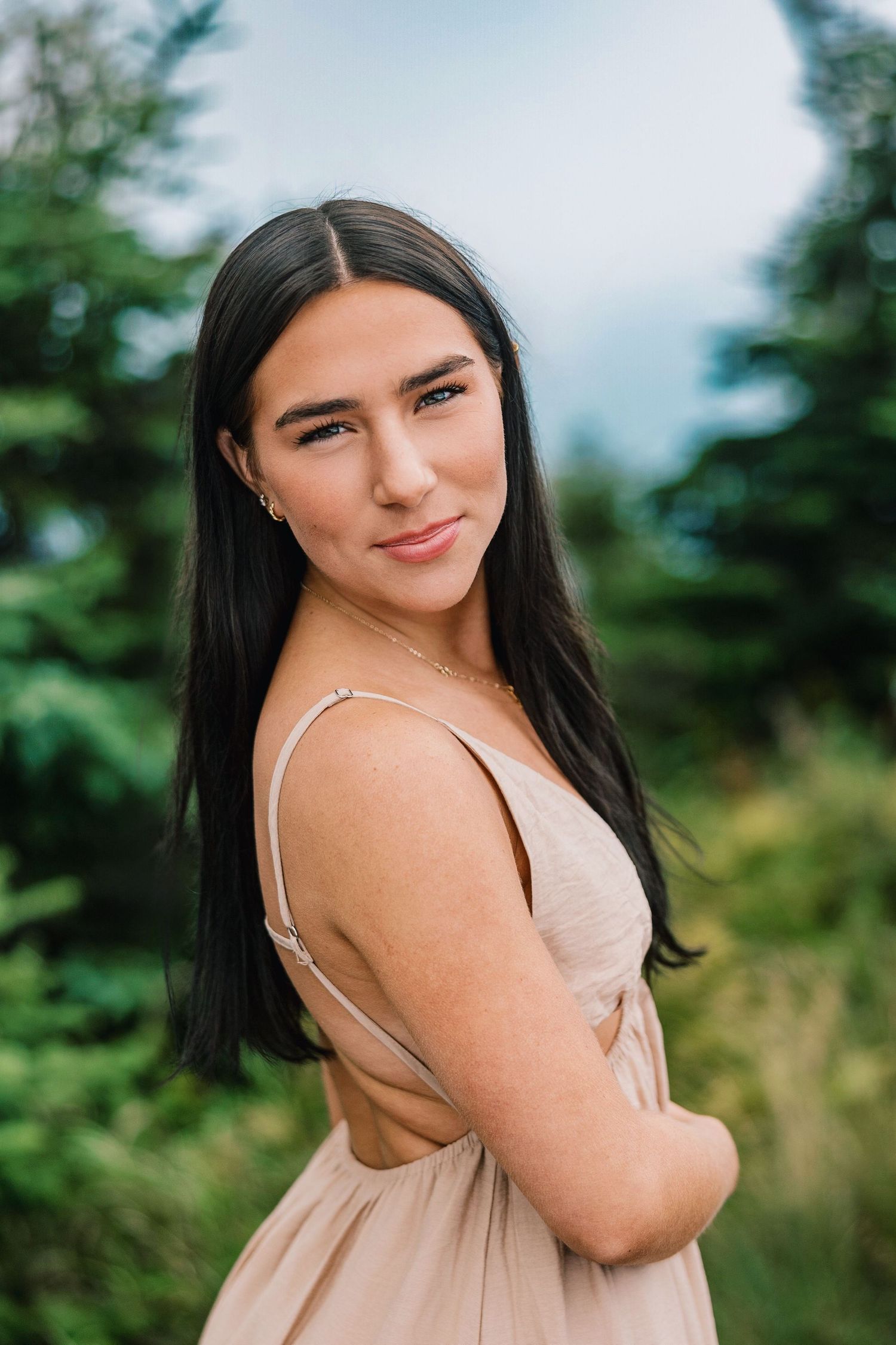 A woman in a beige dress poses outdoors against a natural green background in a series of portrait shots.