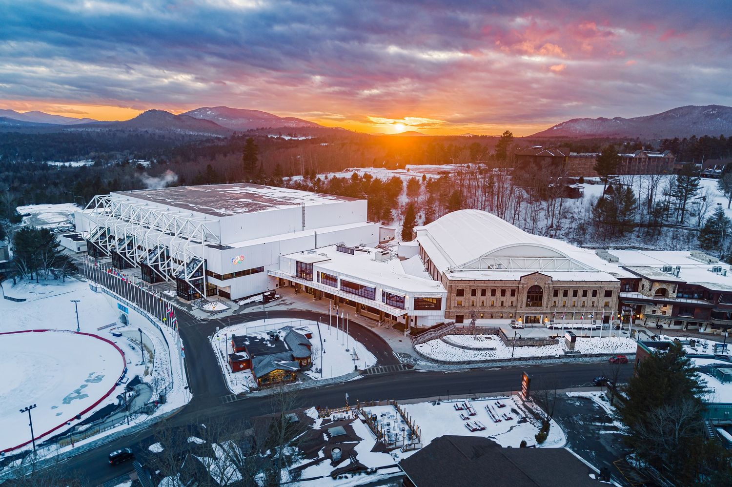 Aerial view of a snow-covered campus building during a vibrant winter sunset in the mountains.