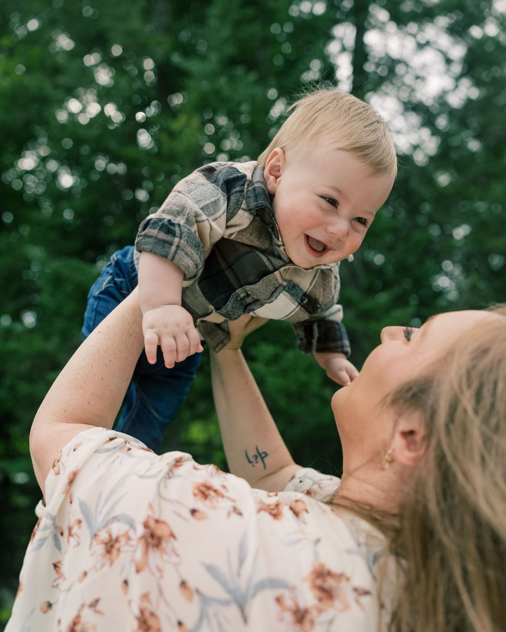 A joyful moment captured between parent and child playing together against a green leafy background.