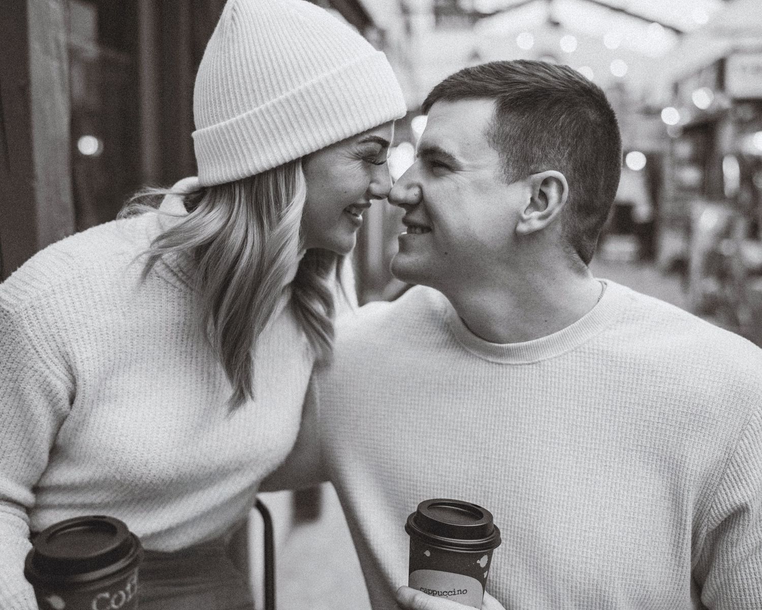 Cozy winter engagement session with couple in matching white sweaters.