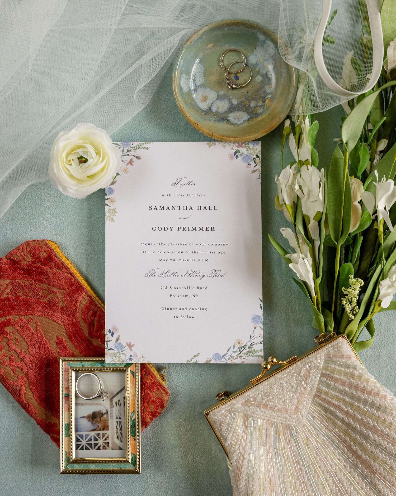 Elegant wedding invitation flatlay for Samantha Hall and Cody Primmer with floral details, rings, white flowers, and vintage accessories.