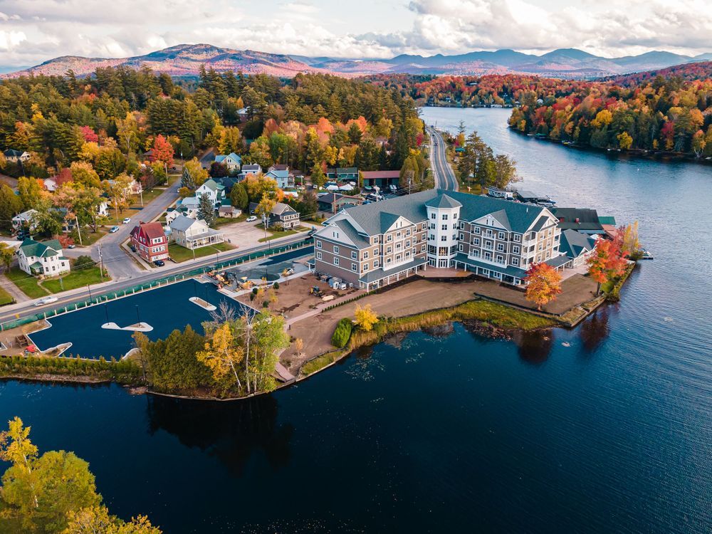 Aerial panoramic view of a lakeside community with colorful fall foliage and waterfront homes during autumn season.