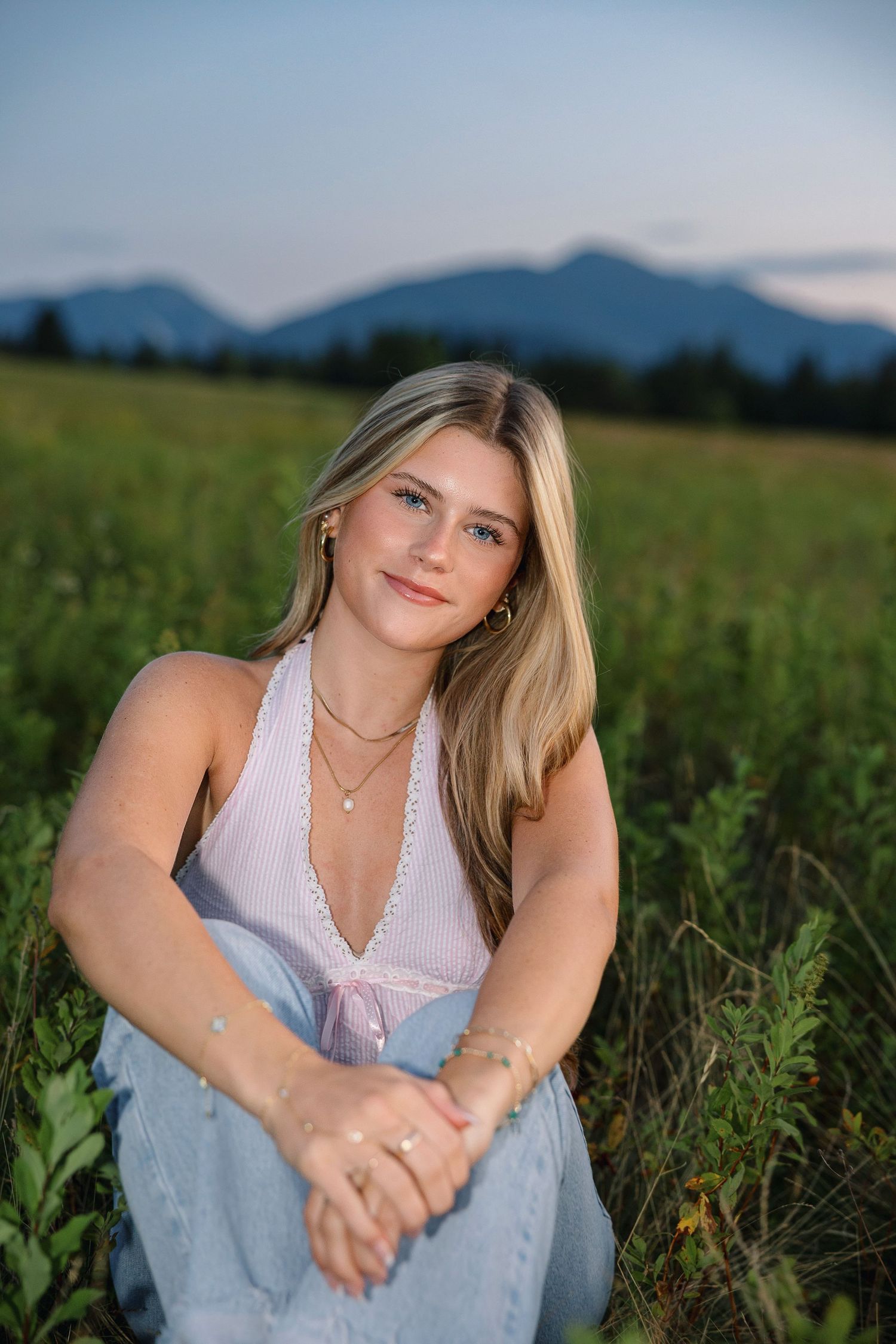 Portrait photos taken at sunset in a grassy field with mountains visible in the background.