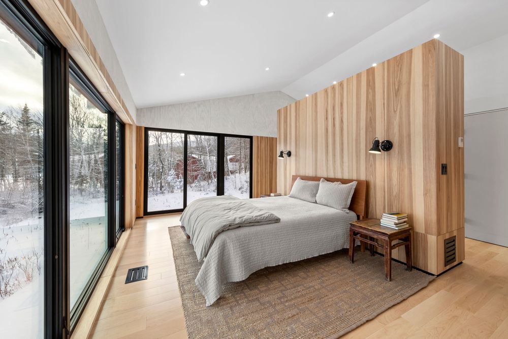 Modern minimalist interior design featuring wood paneled walls and large windows in a bright, open living space.