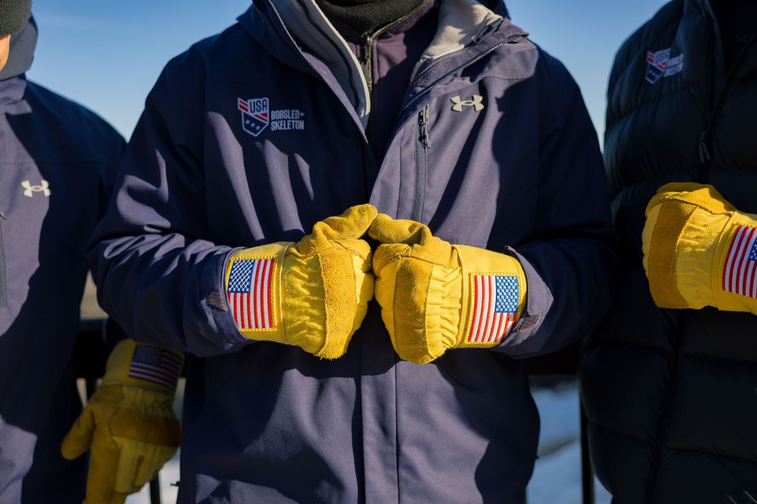 A row of military service members in dress uniforms stand at attention with yellow gloves and American flag patches.