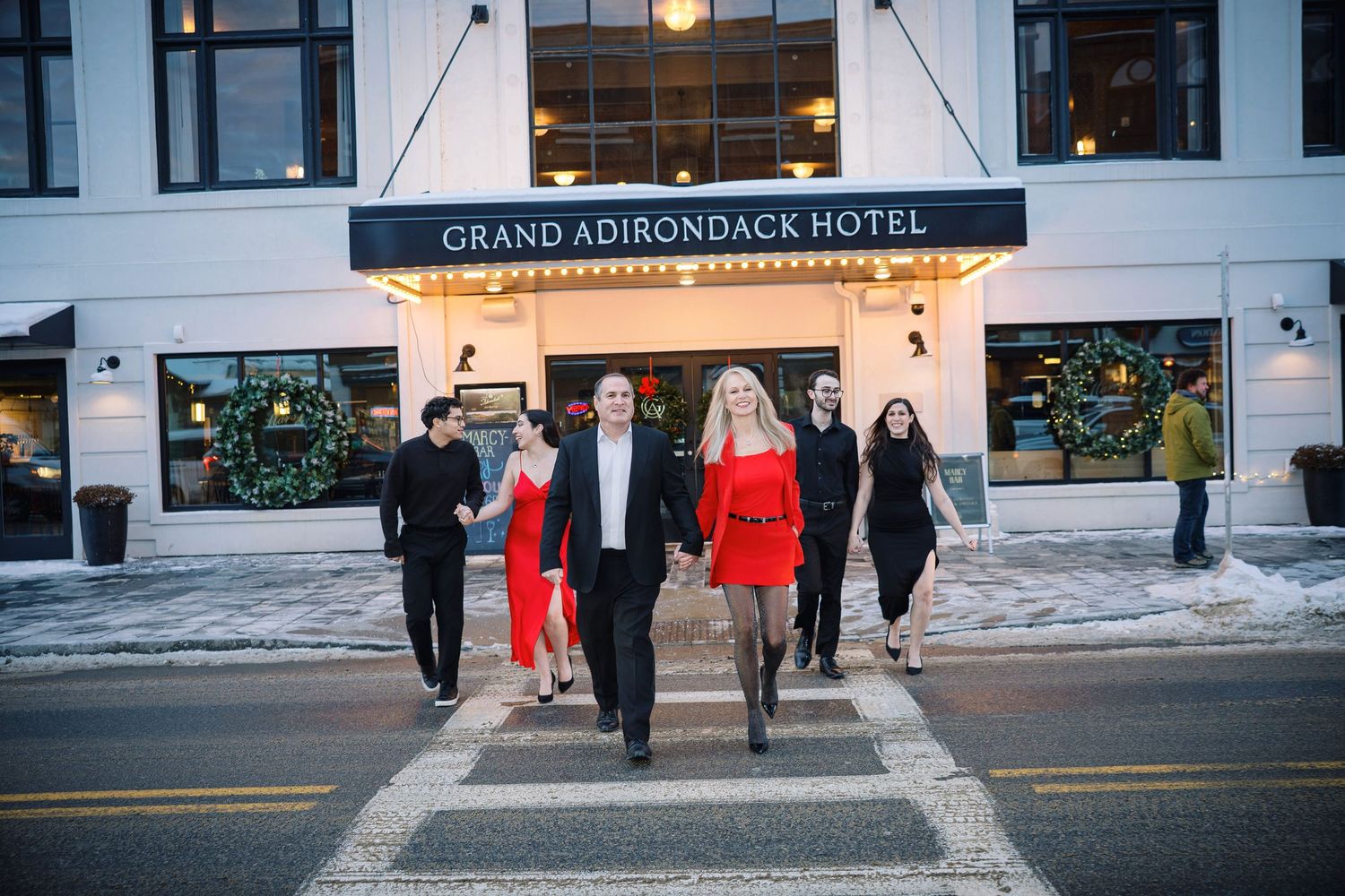 Wedding party walks outside the Grand Adirondack Hotel in Lake Placid during a winter evening celebration.
