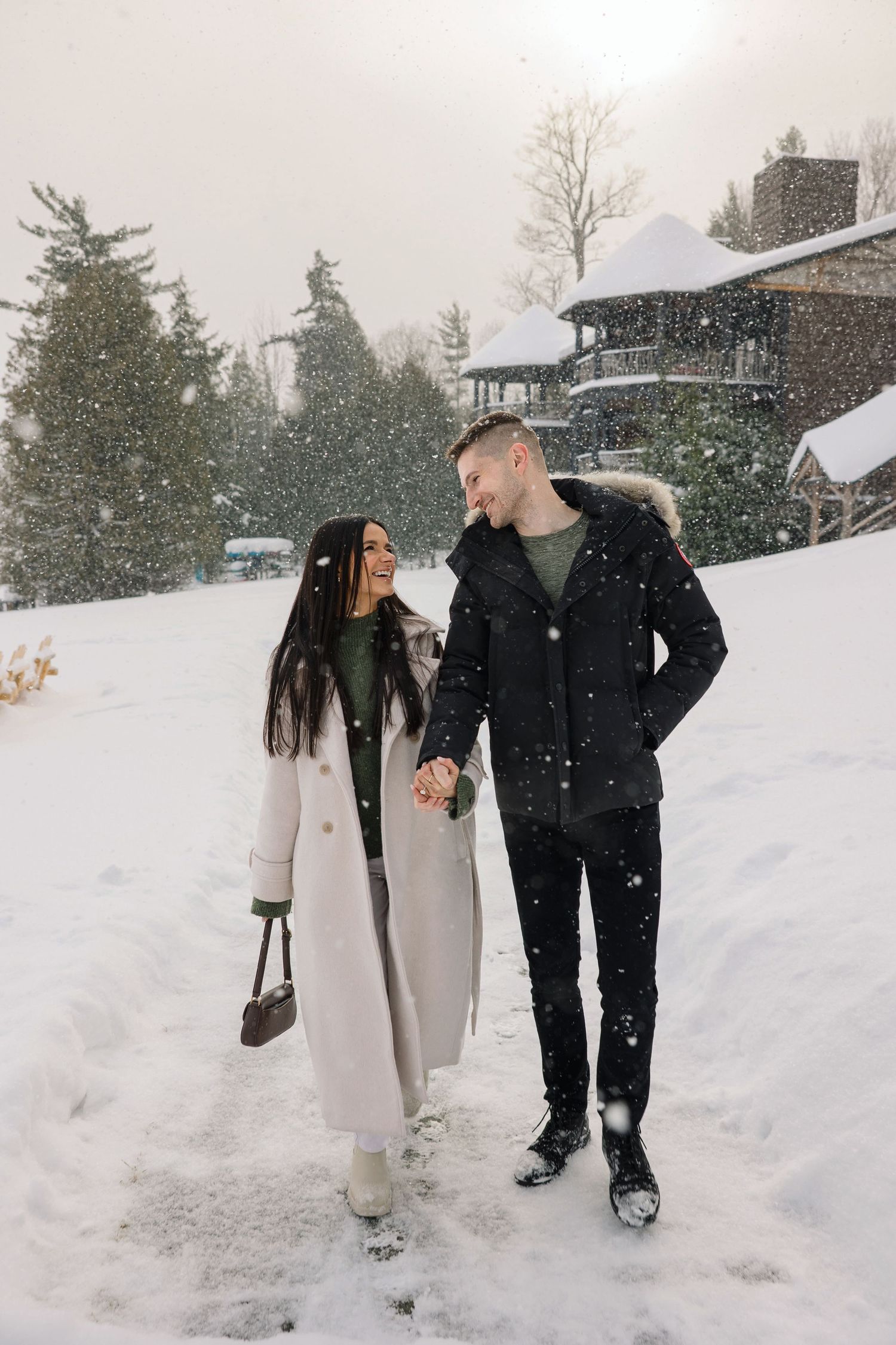 A couple walking together in the snow outside a winter lodge.