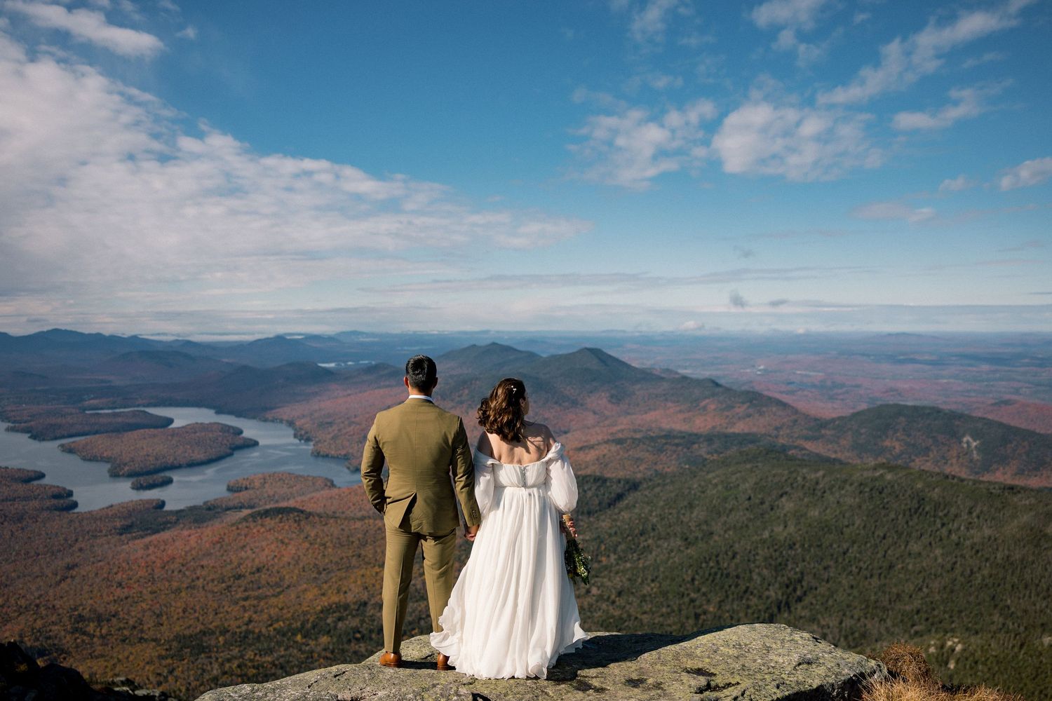 Wedding couple overlooking stunning fall mountain landscape with lake views.