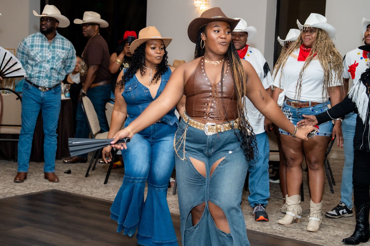 A group of people wearing cowboy hats and western attire dancing at a country music event.