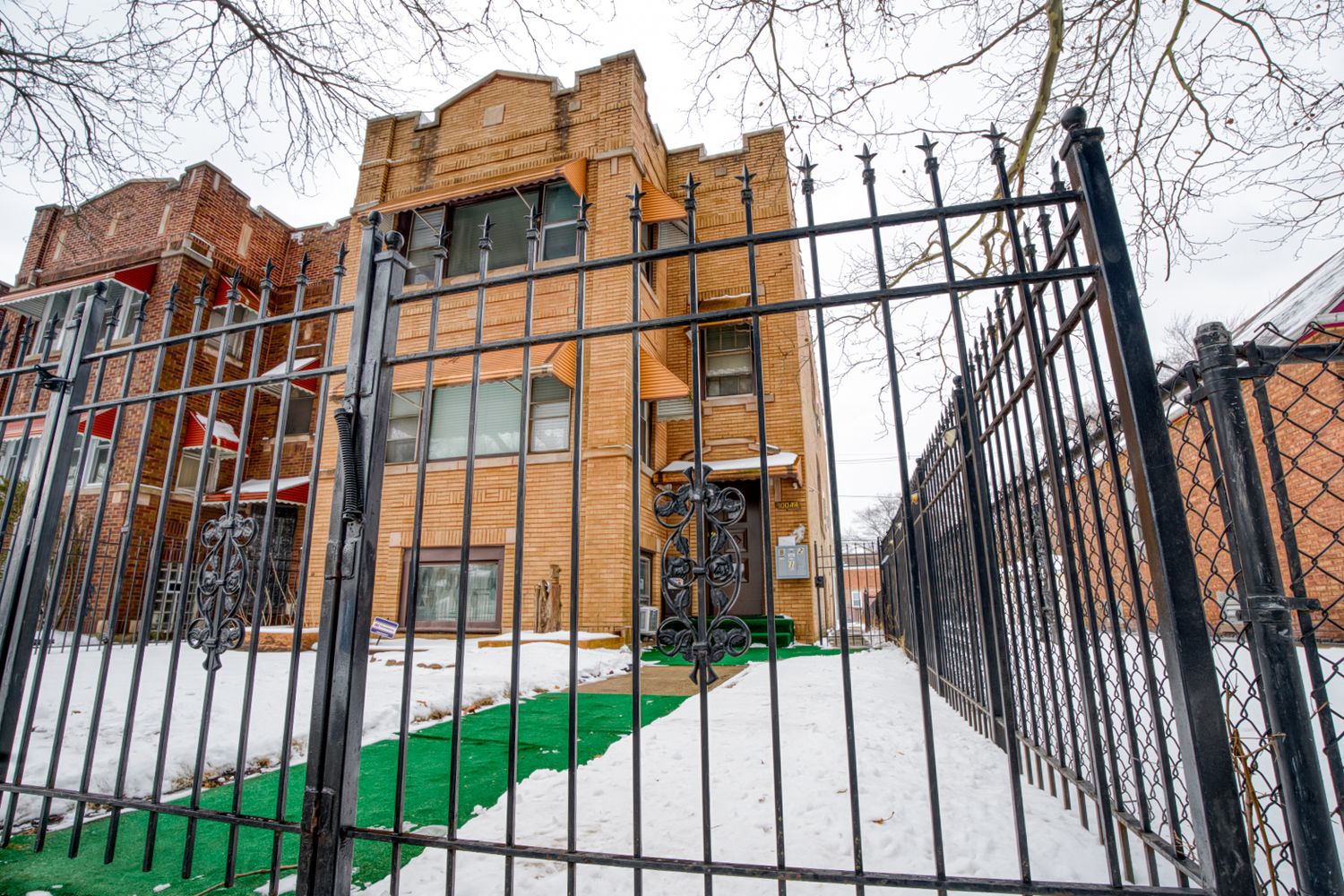Exterior view of brick apartment buildings with black iron fencing in winter.
