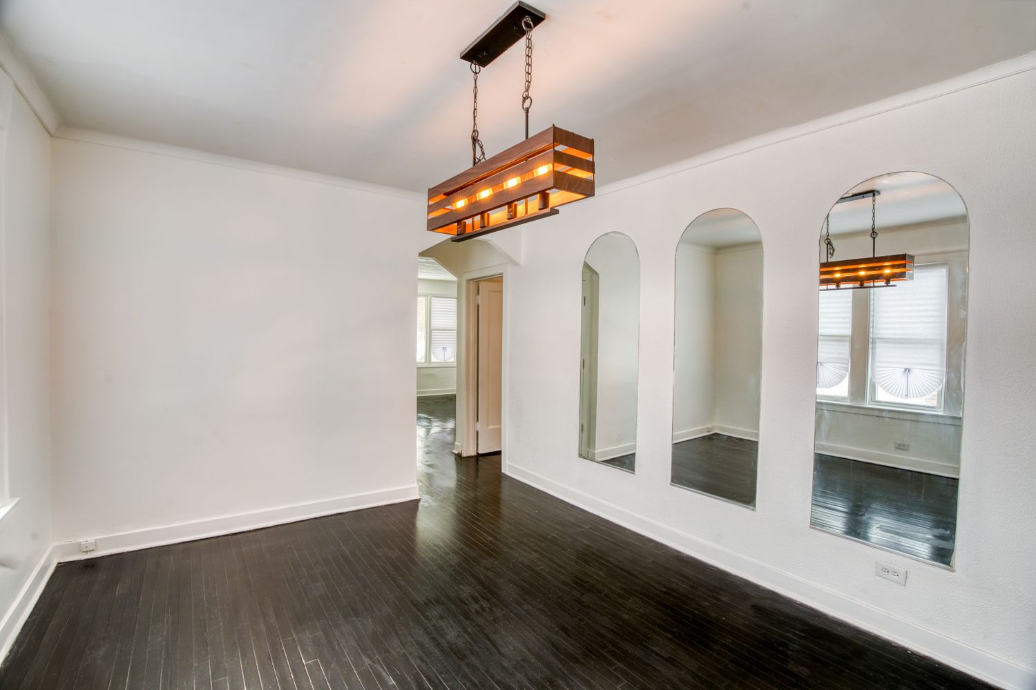 Spacious living area with high ceilings, arched doorways and modern pendant lighting.