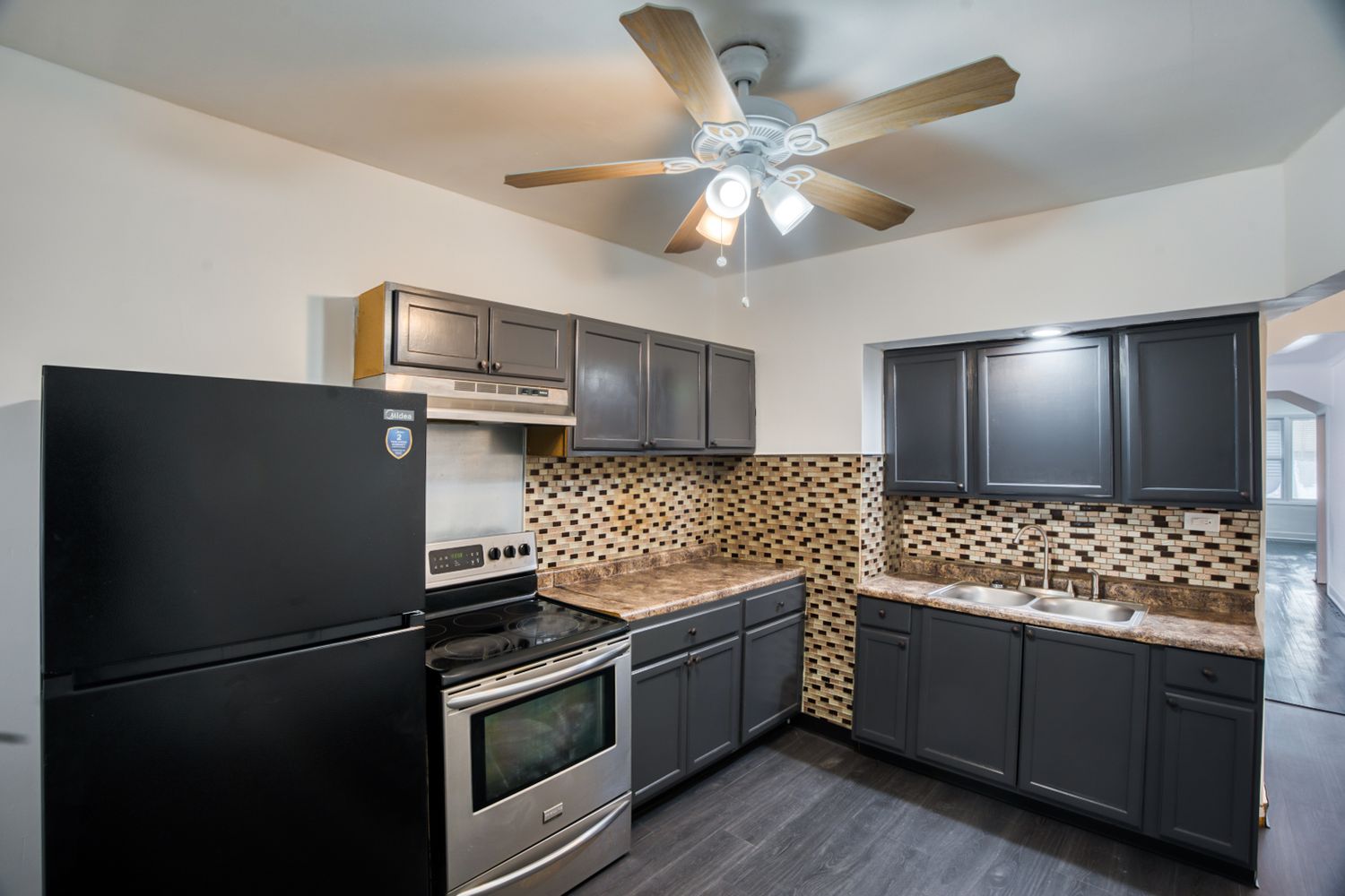 Contemporary kitchen with dark cabinets, stainless appliances and mosaic tile backsplash.