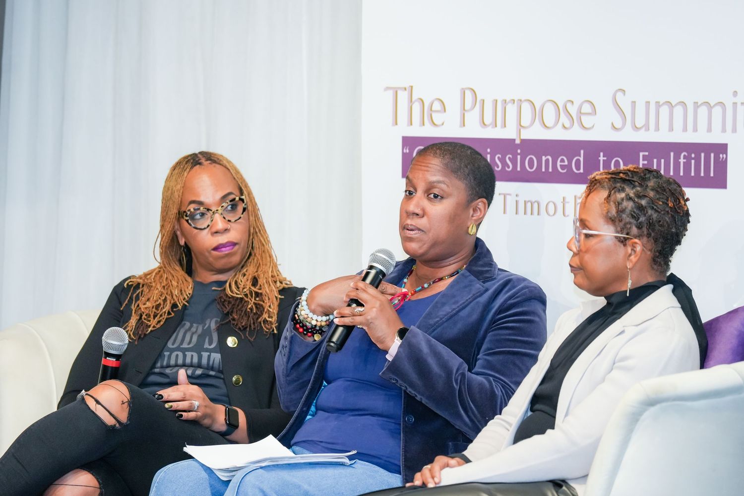 Three speakers engage in discussion during The Purpose Summit conference panel event.