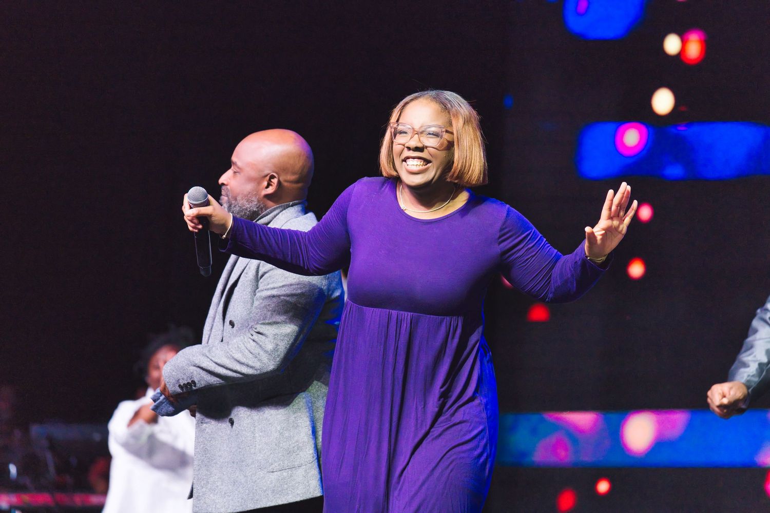 Two performers share an energetic moment on stage during a gospel performance.