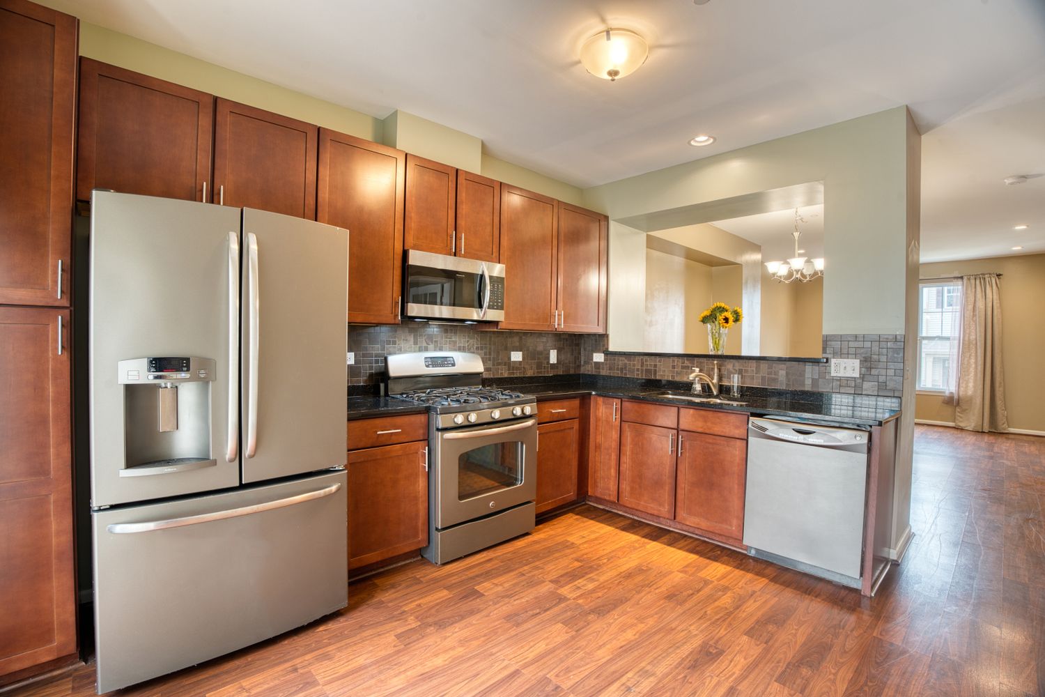 Modern kitchen with stainless steel appliances, wood cabinets, and open concept layout.