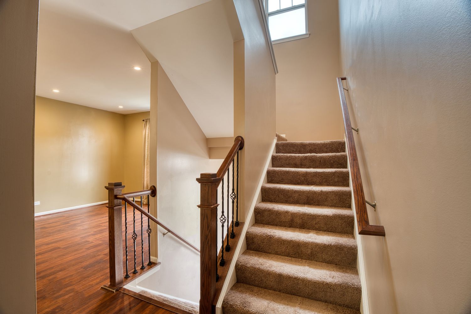 Interior staircase with brown carpeting, white walls, and wooden handrails connecting multiple levels.