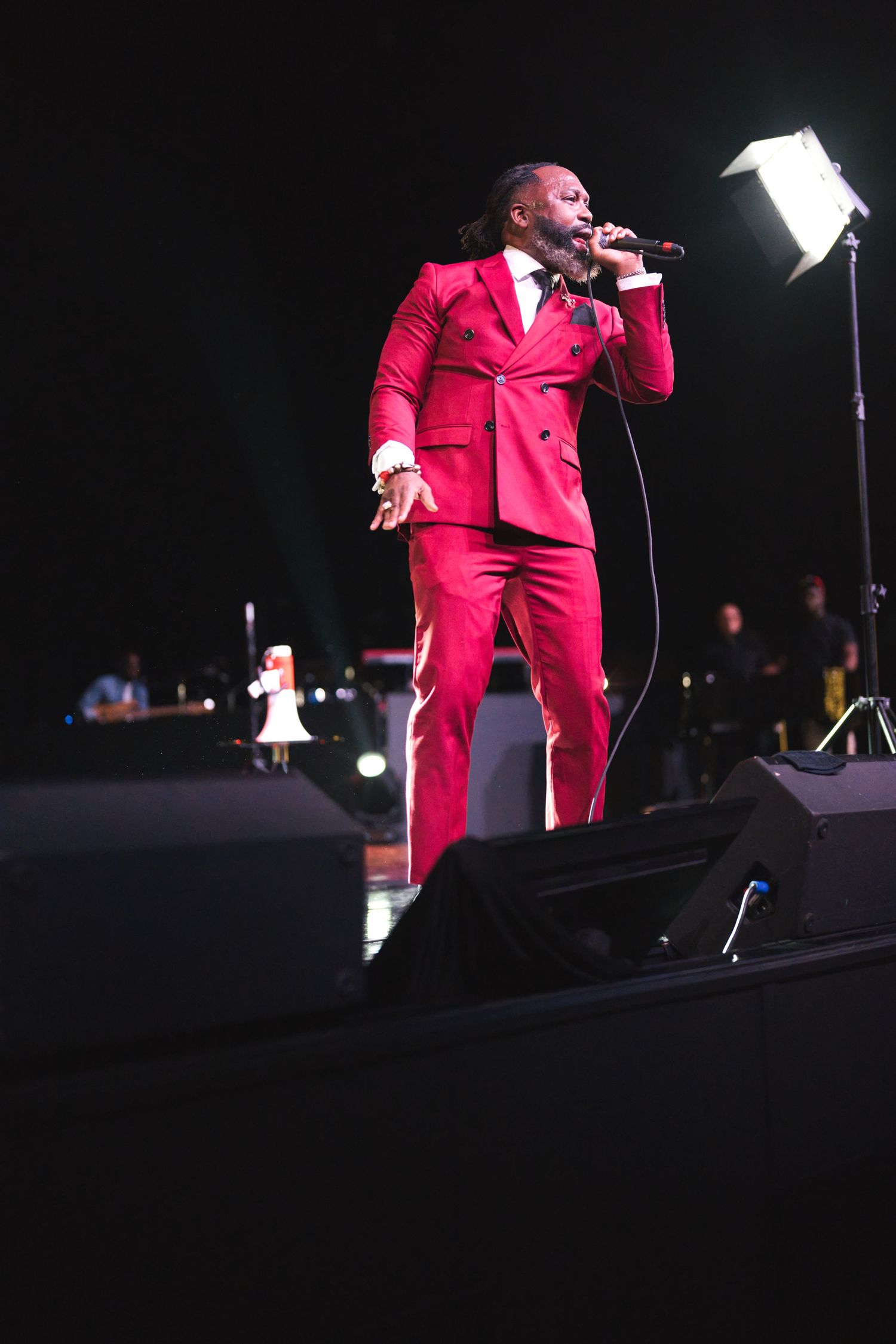 Performance on stage in bright red suit under dramatic lighting.