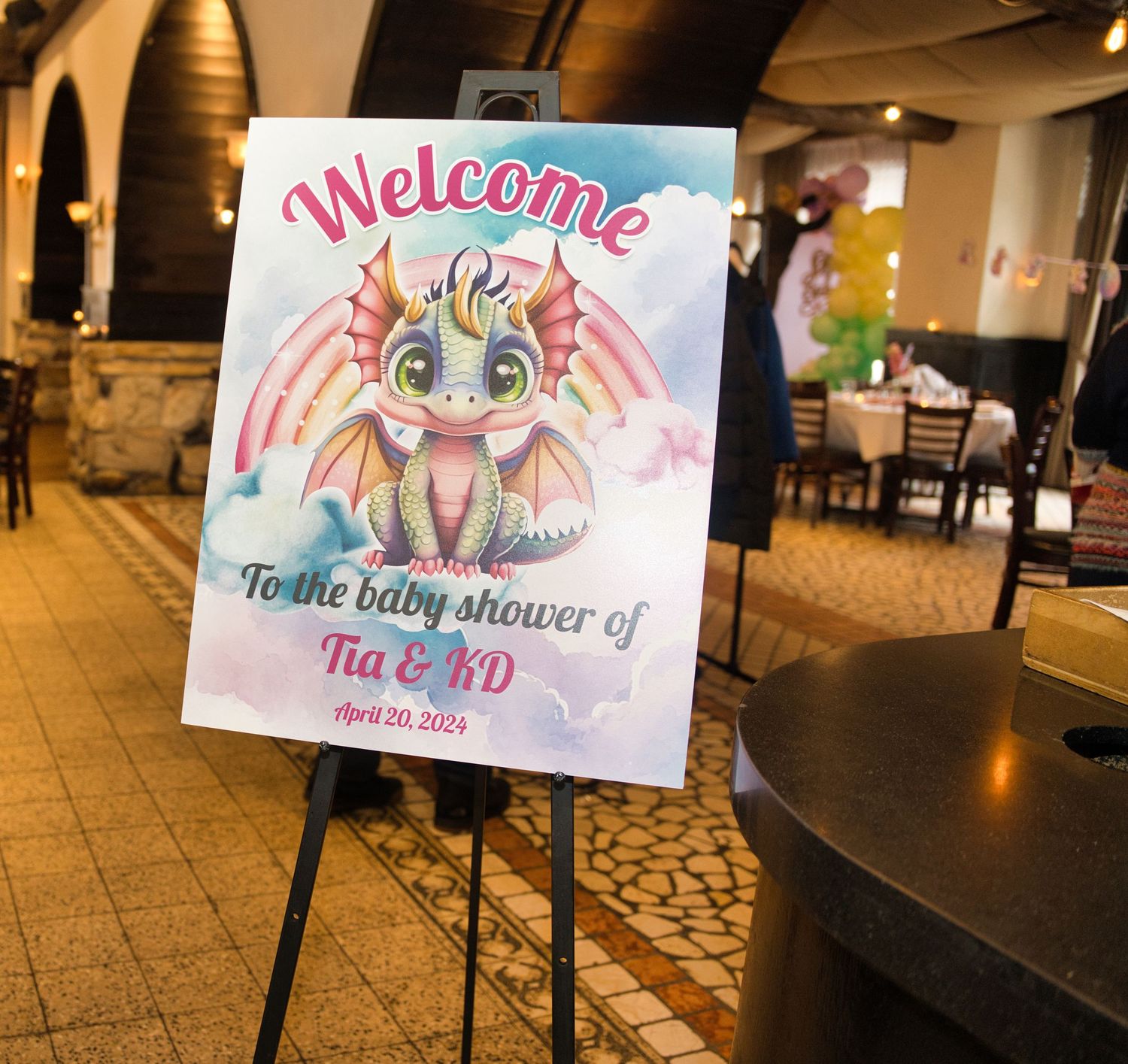 Welcome sign and decorative artwork displayed at a baby shower with pink and blue color scheme.