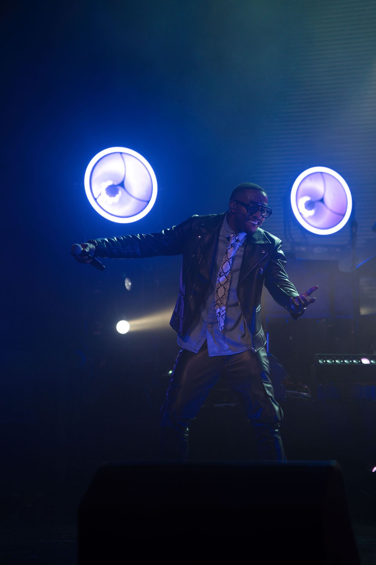 Dynamic stage performance with dramatic blue lighting and fog effects.