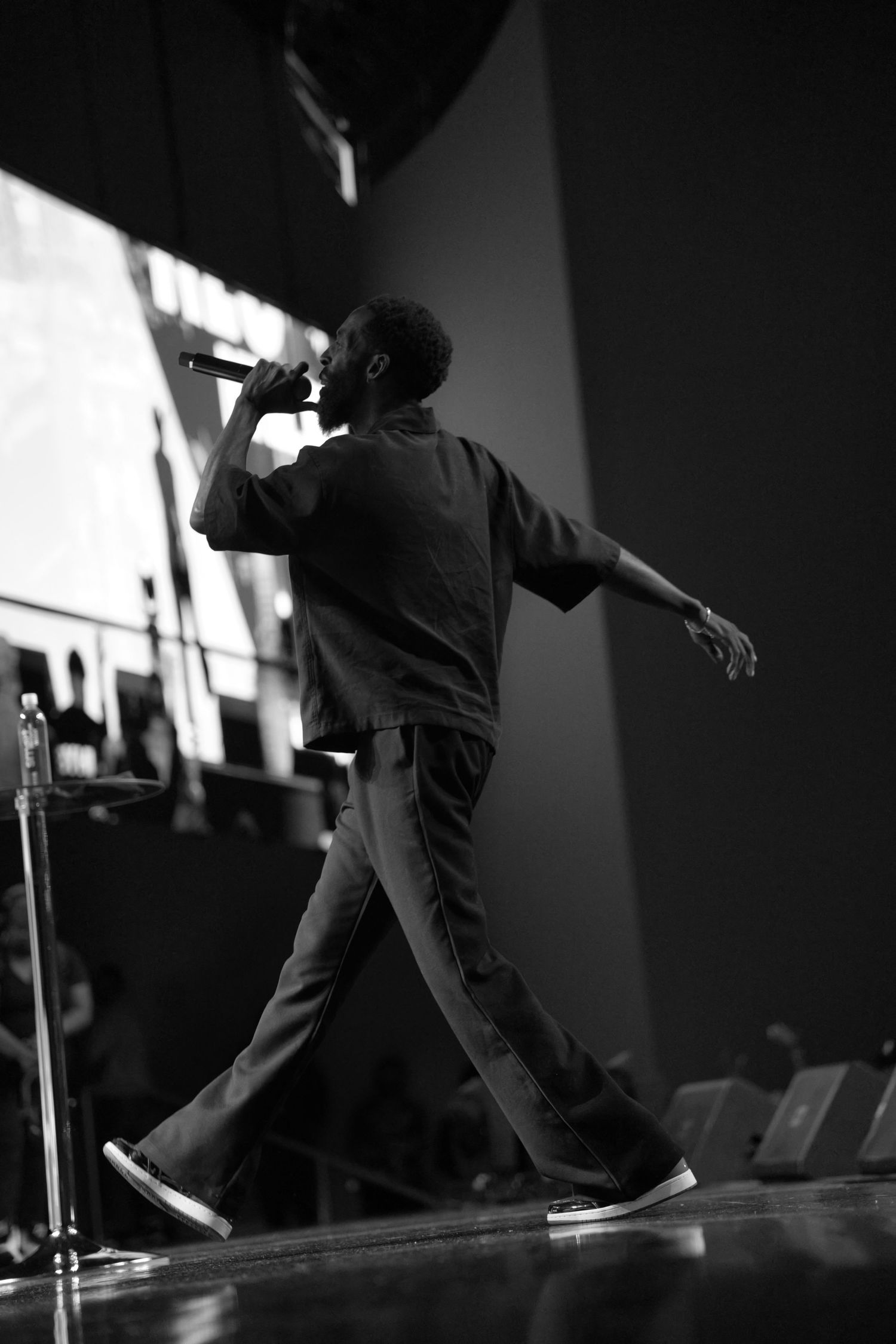 Low-angle black and white shot of a performer in dynamic motion on stage.
