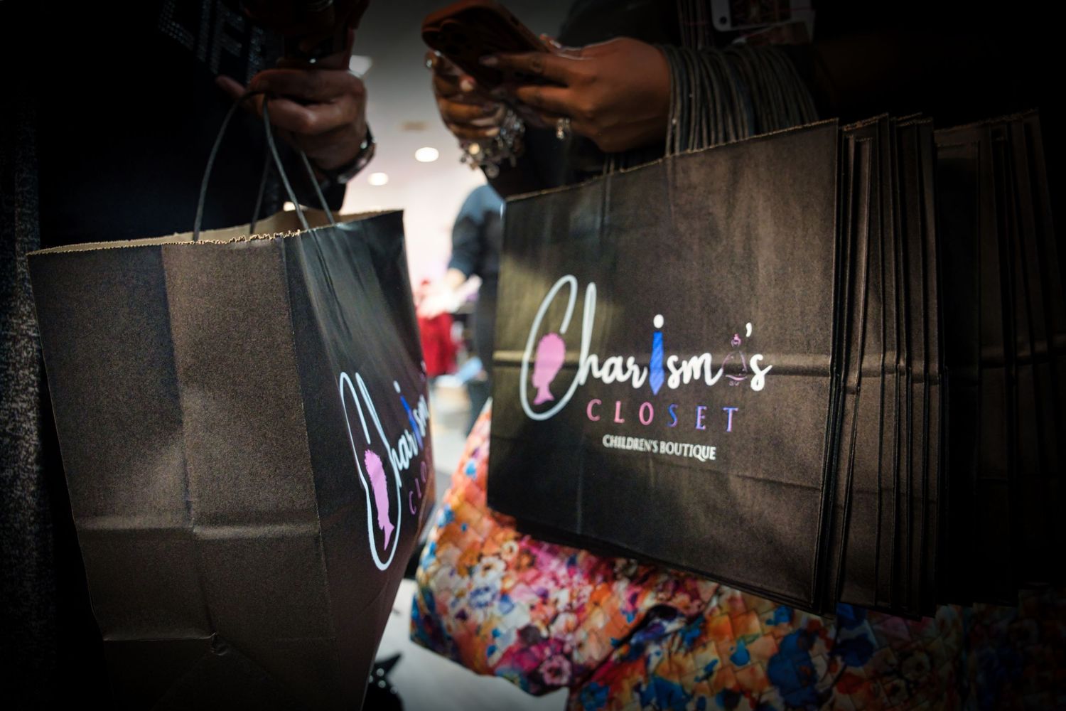 A black leather handbag with colorful floral patterns displayed in a retail store setting.