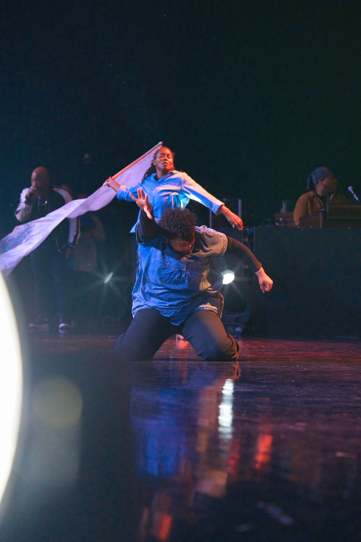 Modern dance routine on dark stage with blue lighting effects.