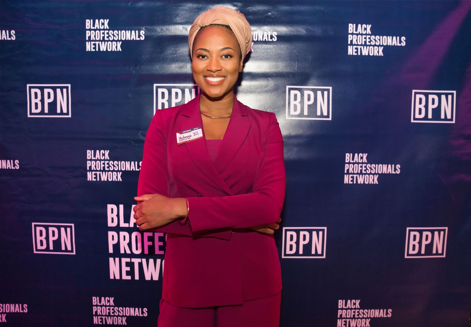 Person in red outfit poses against backdrop with BPN logos at media event.