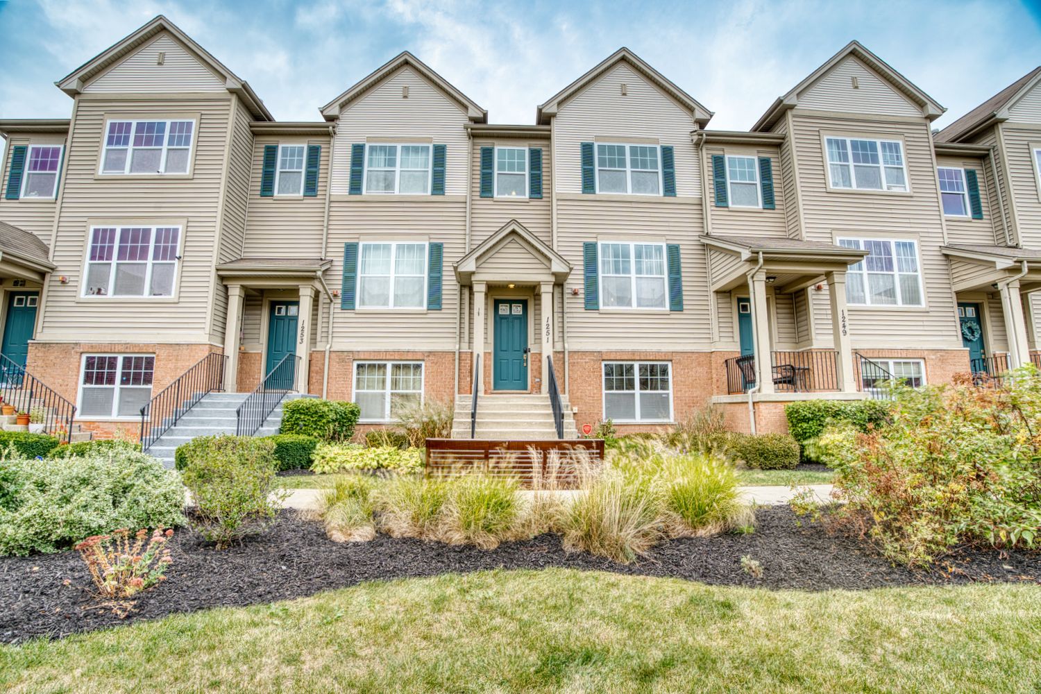 Row of modern townhomes with grey and beige exterior featuring varied rooflines and landscaping.