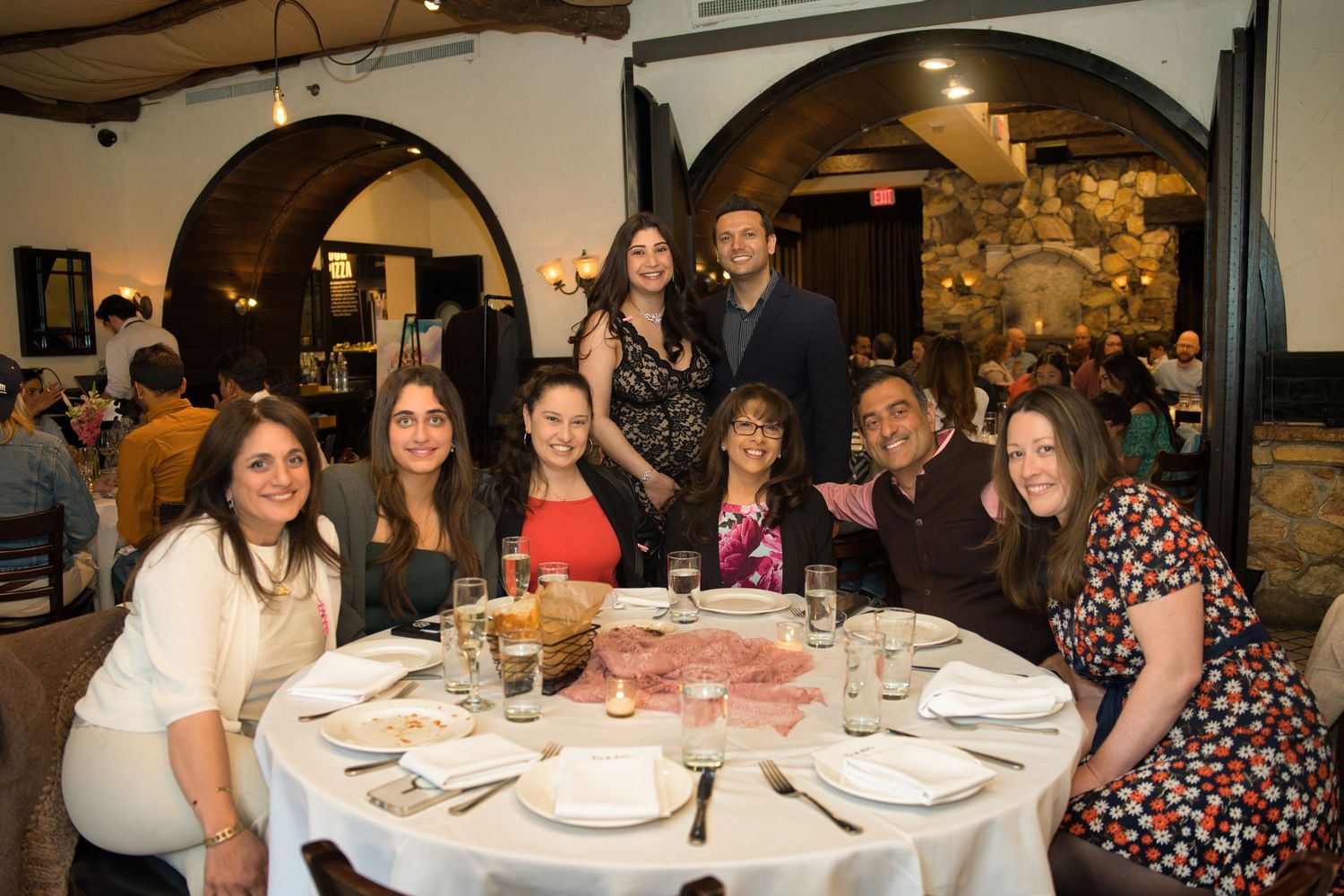 A group of people gathered around dining tables at a formal event in an indoor venue.