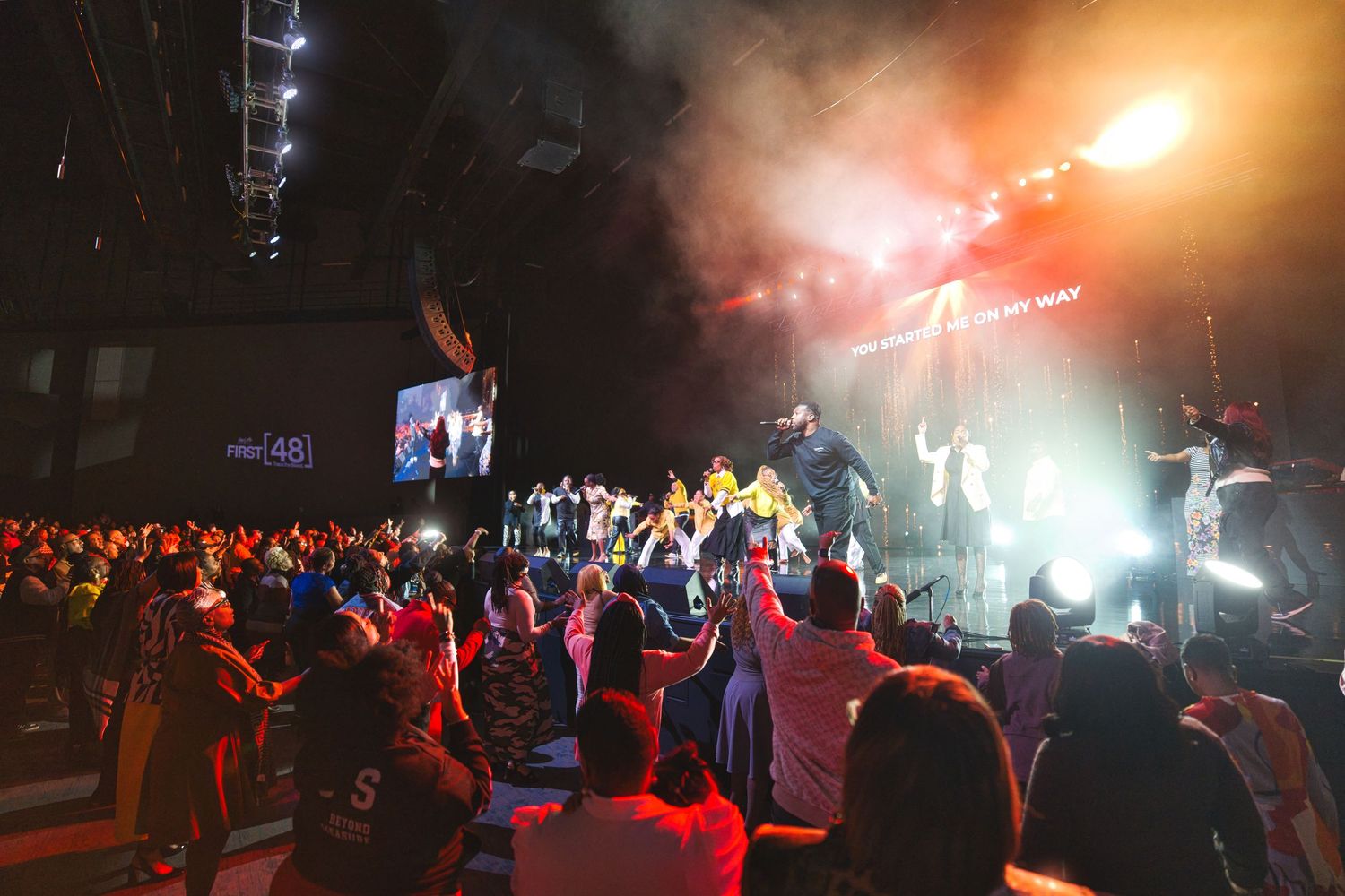 Energetic concert crowd enjoying a live performance with dramatic lighting and smoke effects on stage.
