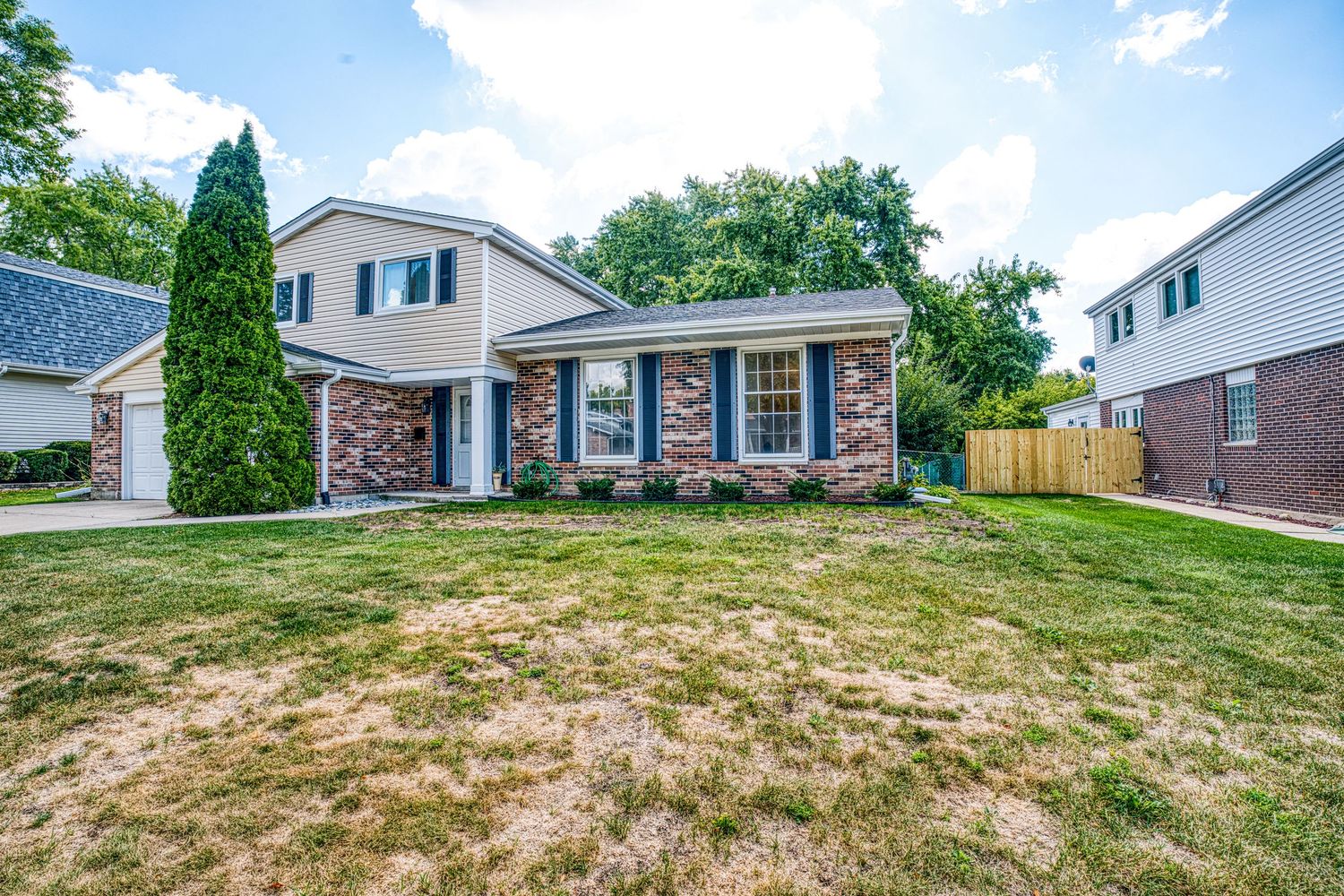 Two-story suburban house with brick facade and well-maintained landscaping.