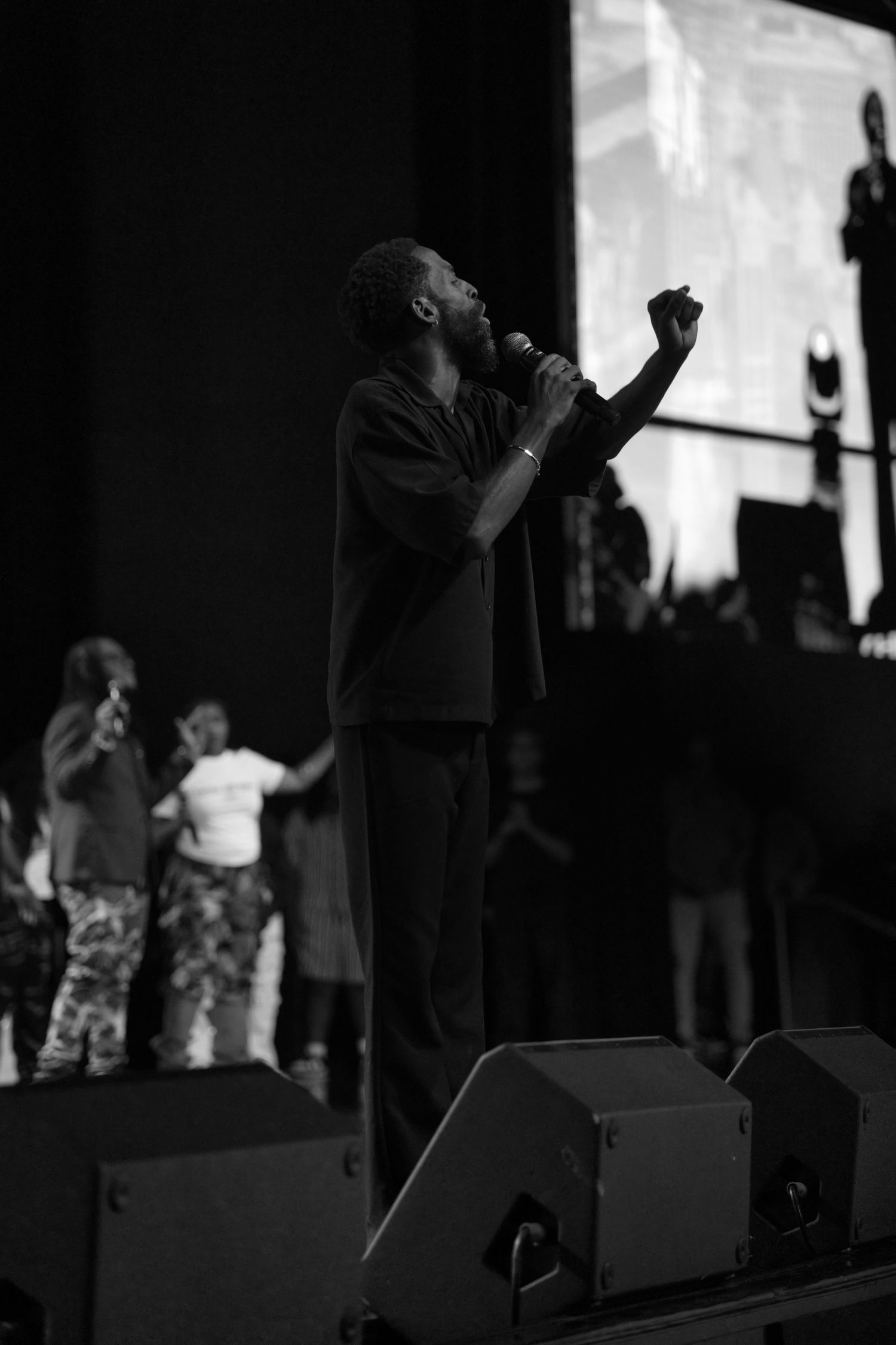 Black and white concert scene showing performers and audience members in silhouette.