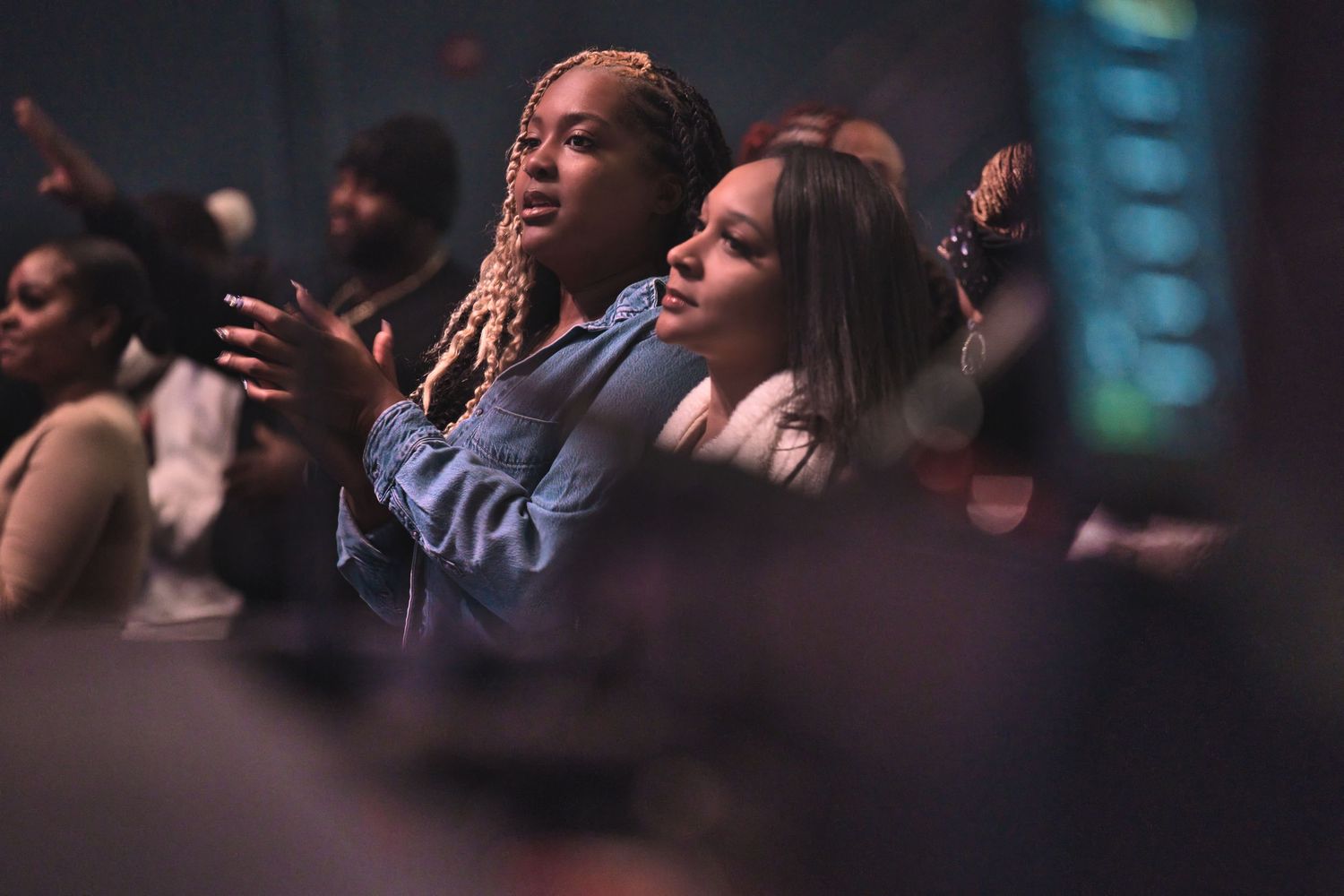 People worshipping with raised hands during an emotional church service.