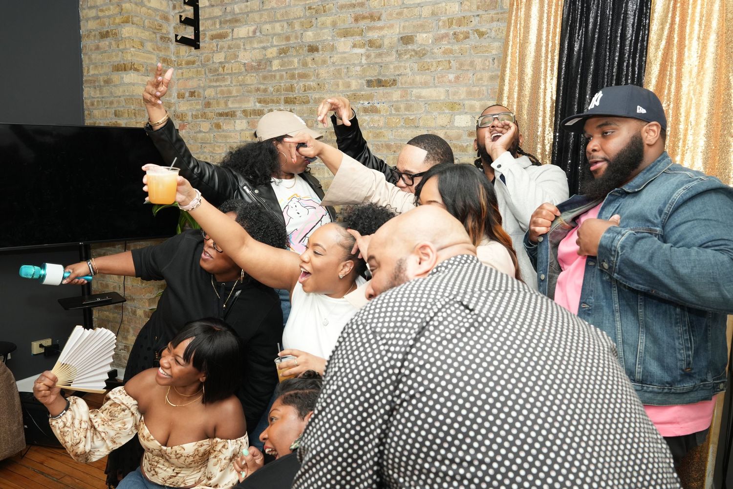 Group of people enthusiastically worshipping with raised hands in brick-walled room.