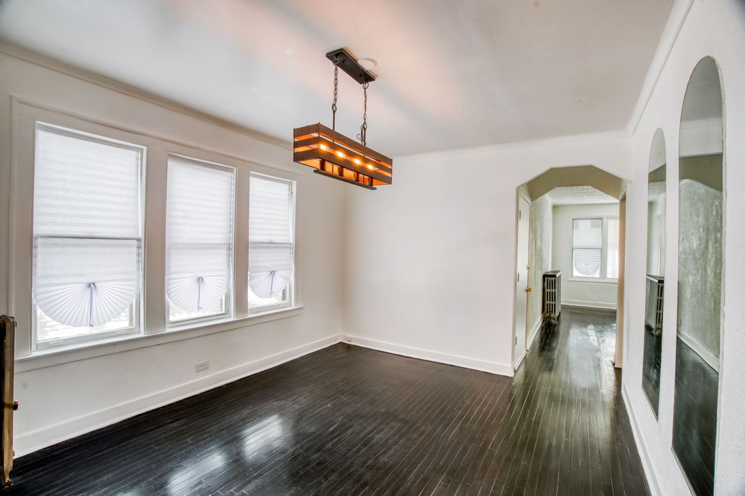 Open concept living space with white walls and dark hardwood flooring.