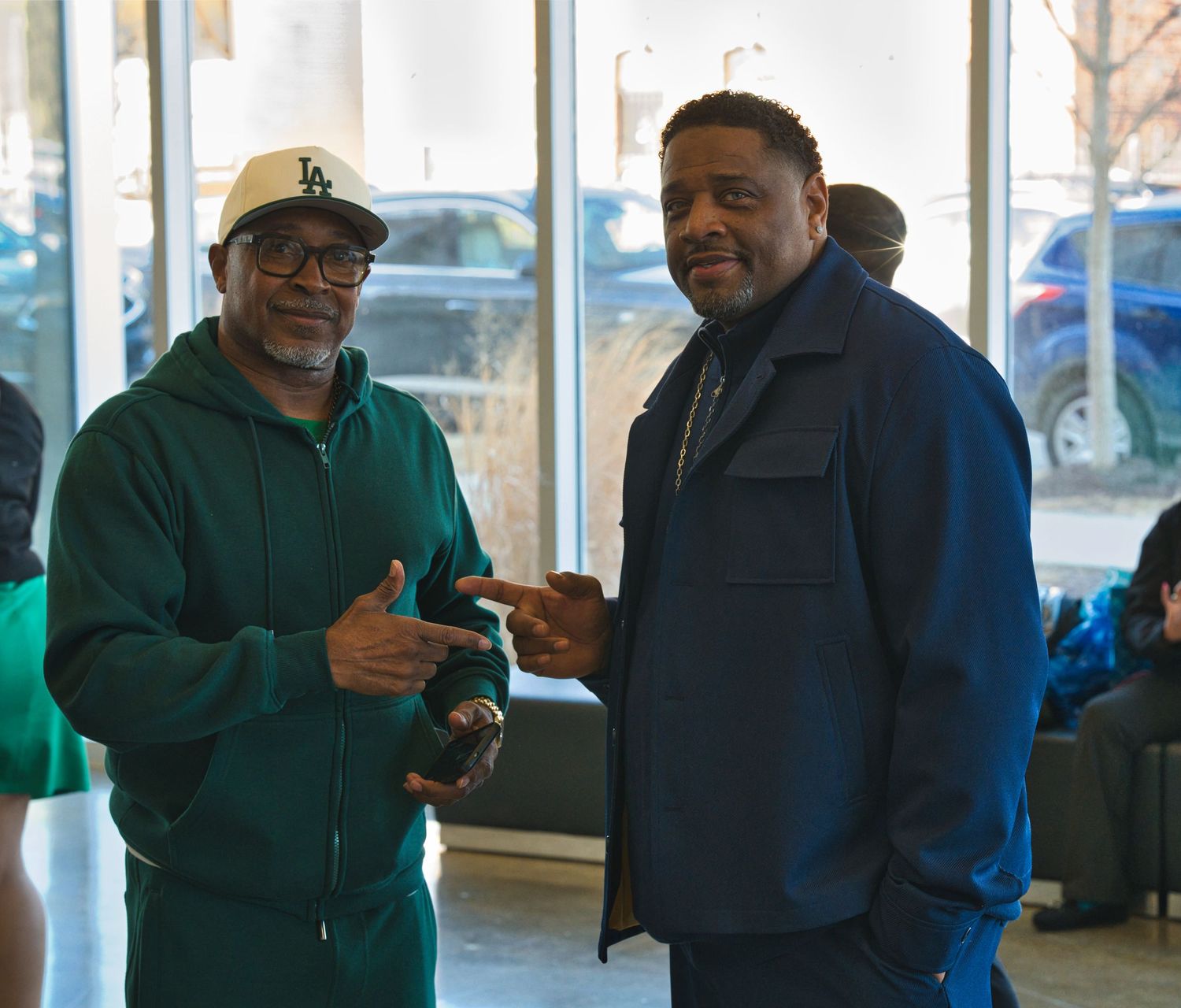 Two people in winter coats stand and talk while gesturing during a conversation.