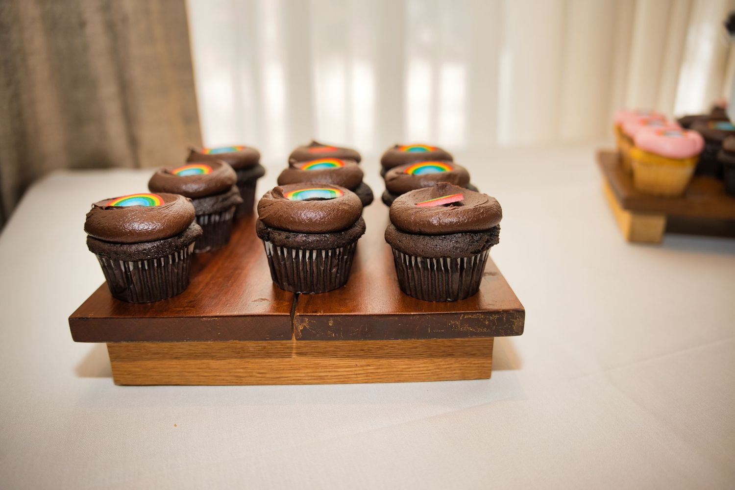 Chocolate cupcakes with chocolate frosting arranged on wooden serving boards in a rustic setting.