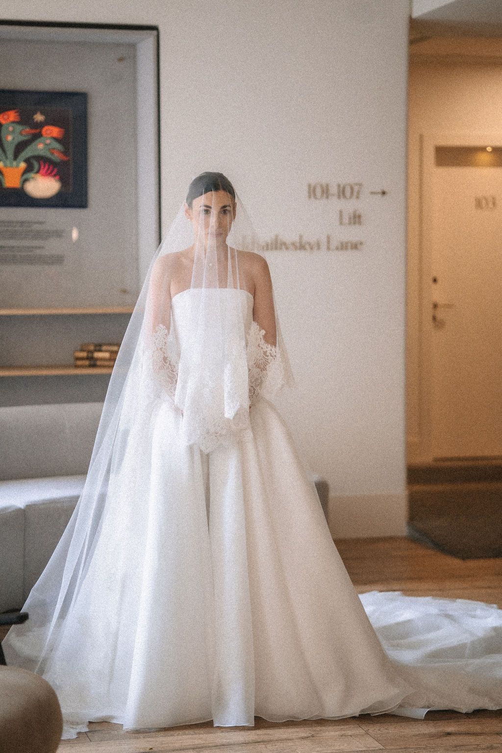 A sequence of five photos showing a flowing white wedding gown with a long train displayed in an indoor setting.