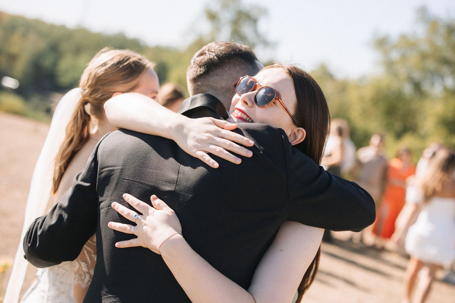 A series of candid black and white photos showing people embracing in an outdoor setting during a celebration.