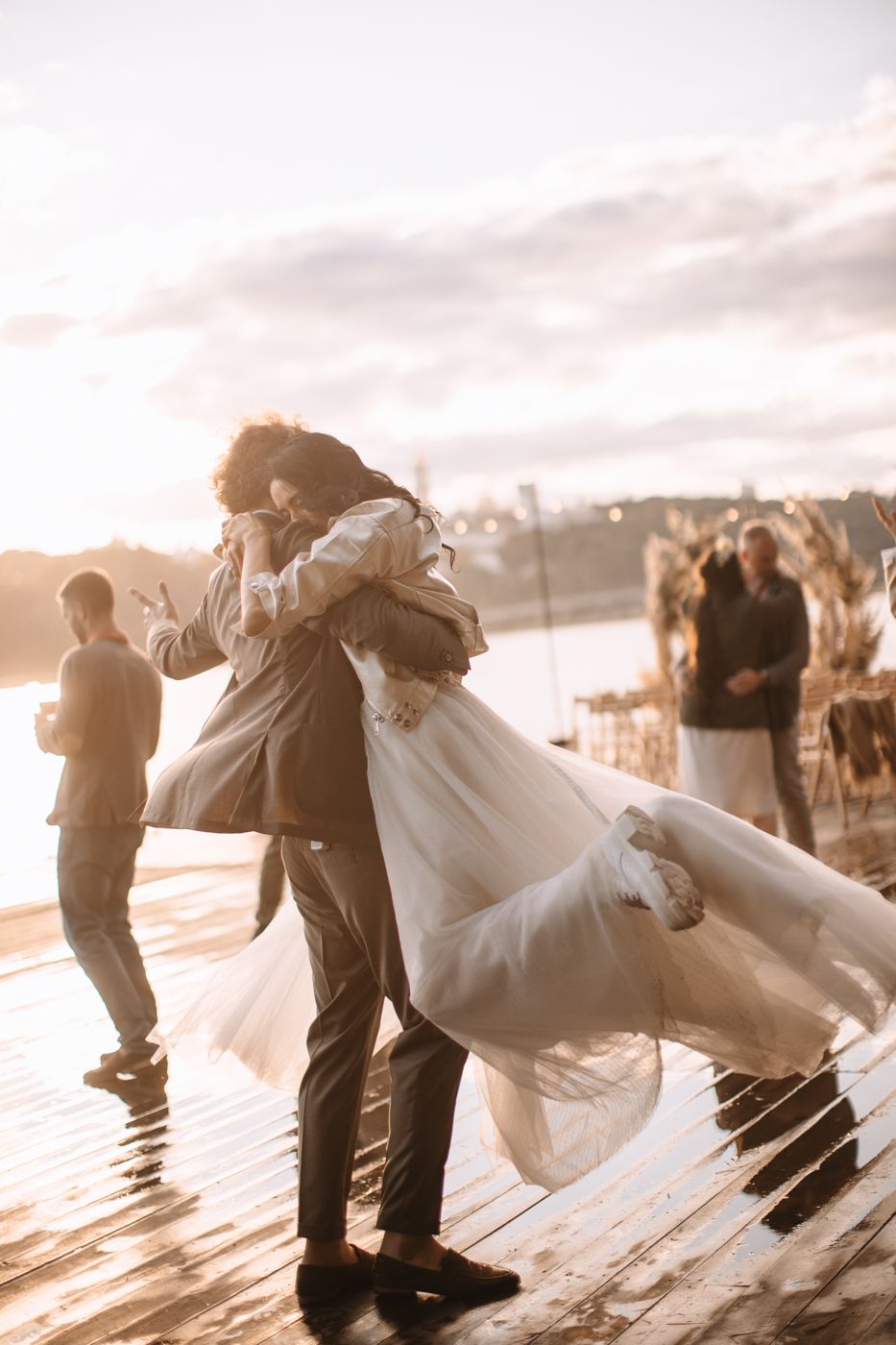 A romantic sunset dance on a wooden dock with a flowing white dress catching the golden light.