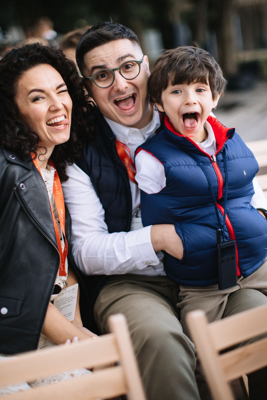 A joyful family portrait session showing candid laughter and embraces on a wooden bench.