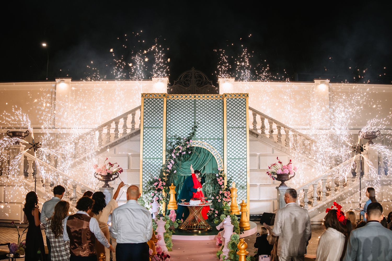 A group celebrates at an elegant wedding reception venue with string lights and white decor creating a festive atmosphere.