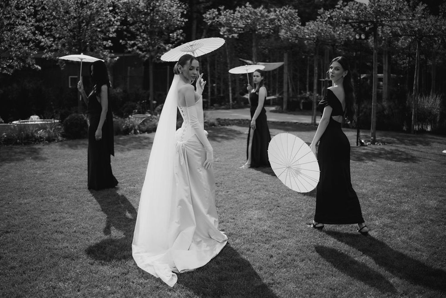 Black and white photo of a dance performance with silhouettes of people and umbrellas in an outdoor setting.