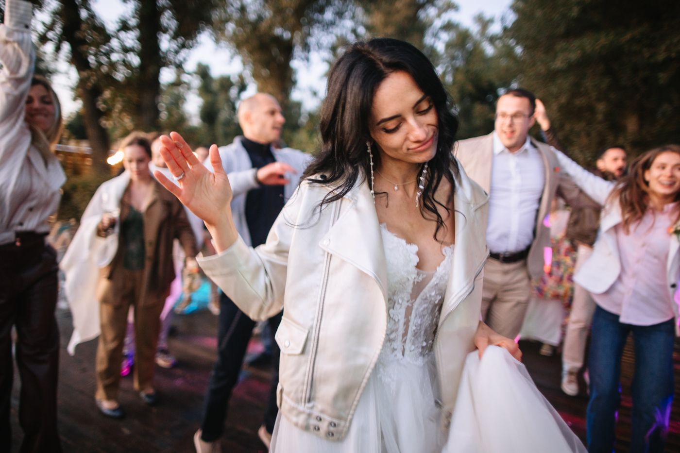 Wedding guests dance and celebrate on an outdoor dance floor during an evening reception.