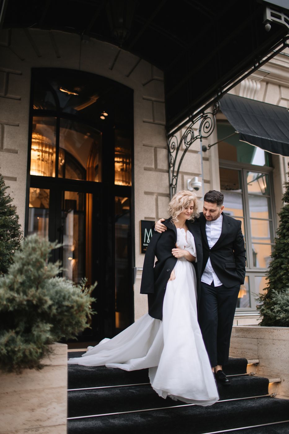 Newlywed couple shares intimate moment on elegant building steps.