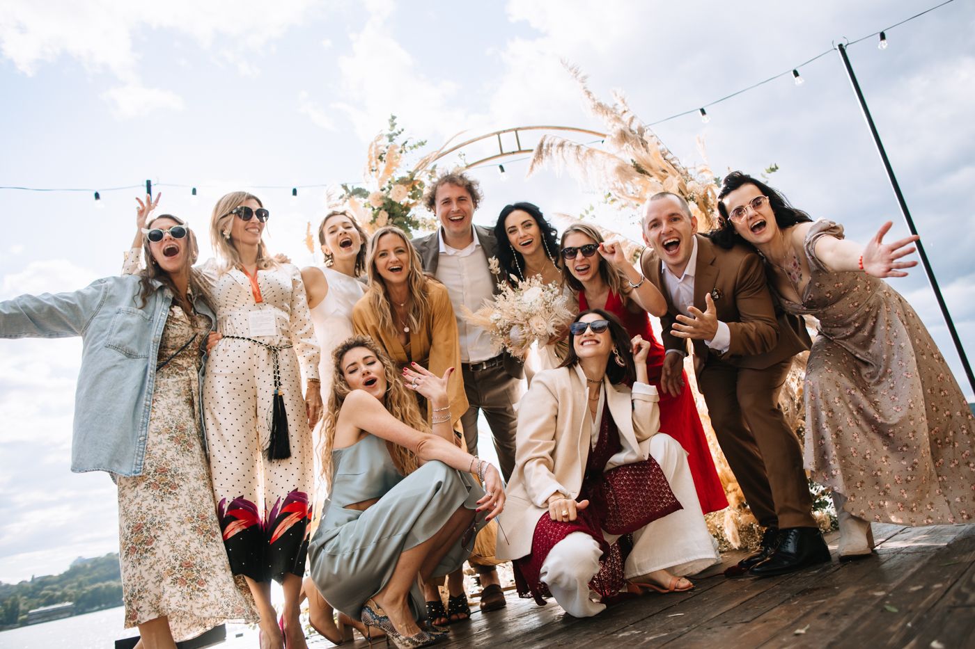 Group of friends in formal attire pose together outdoors in a candid celebration shot.
