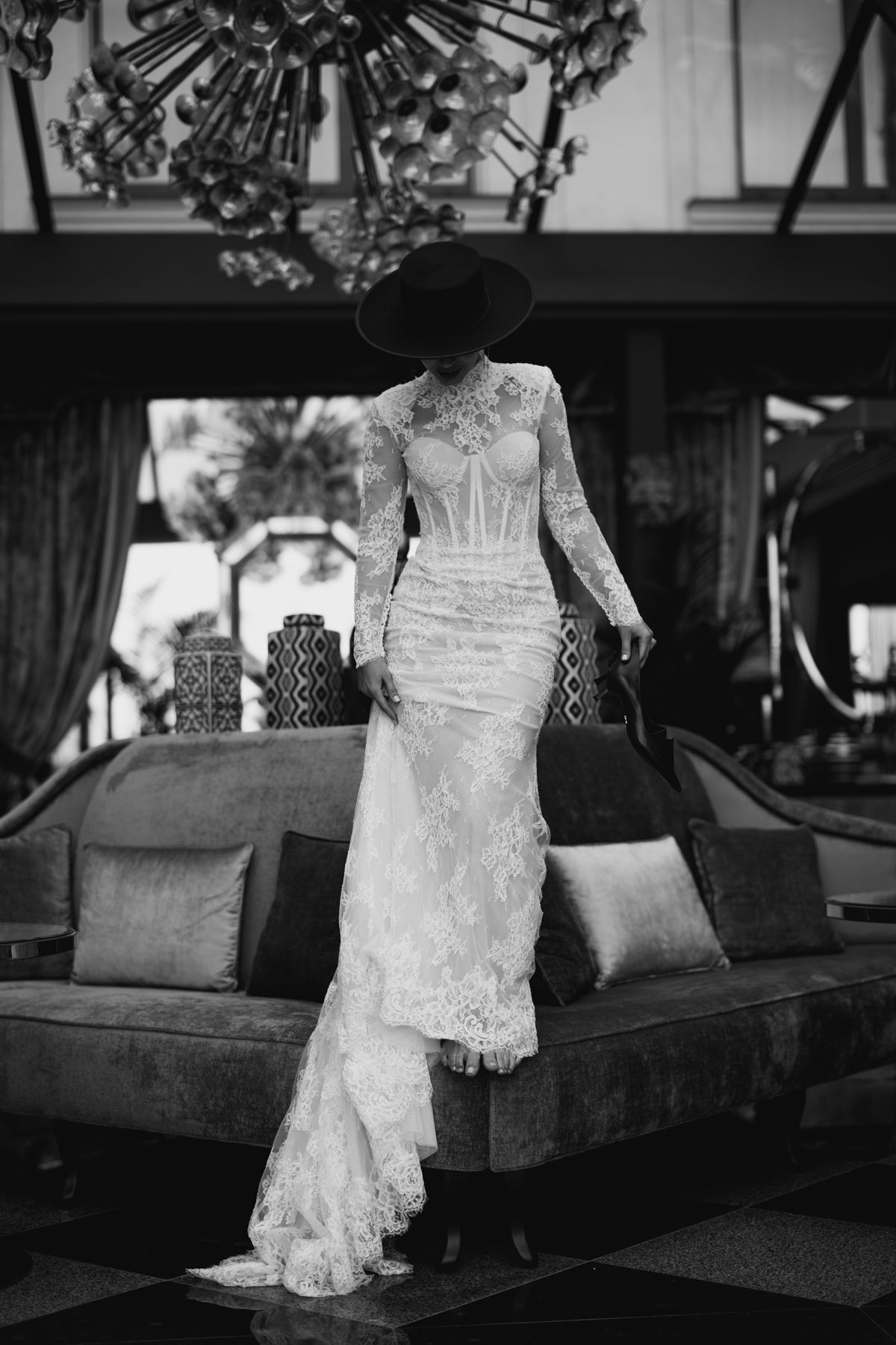 Elegant lace wedding dress with long sleeves and mermaid silhouette photographed in black and white against vintage decor.