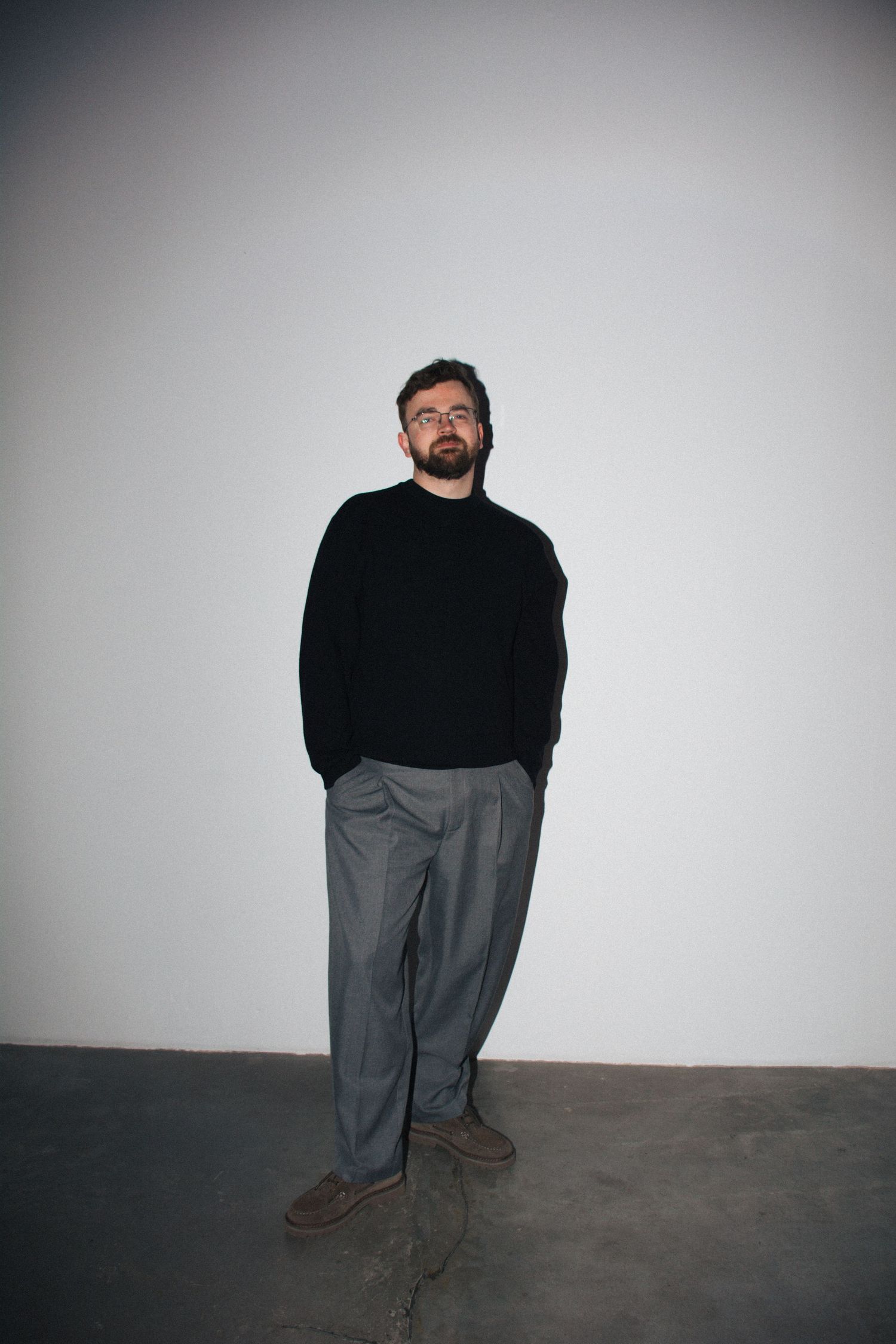 Cropped artistic portrait series showing a person in black sweater and grey pants against white background.