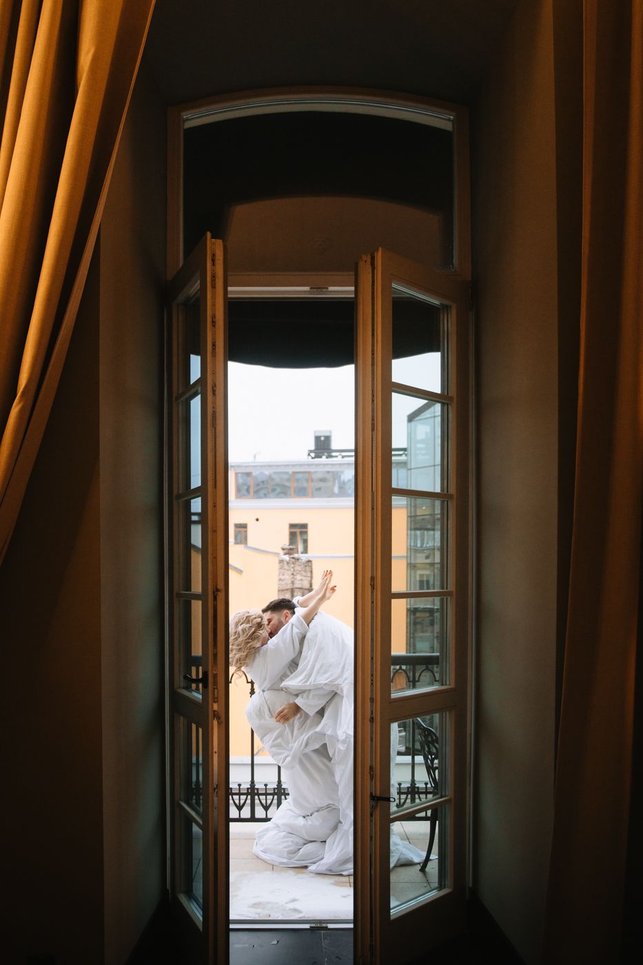 Figure in flowing white dress poses dramatically in window frame sequence.